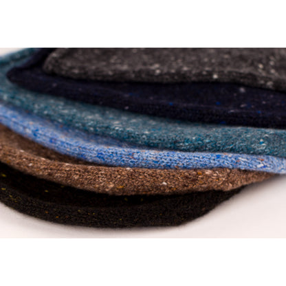 Stack of donegal cashmere tweed beanie hats in various colours on a white background